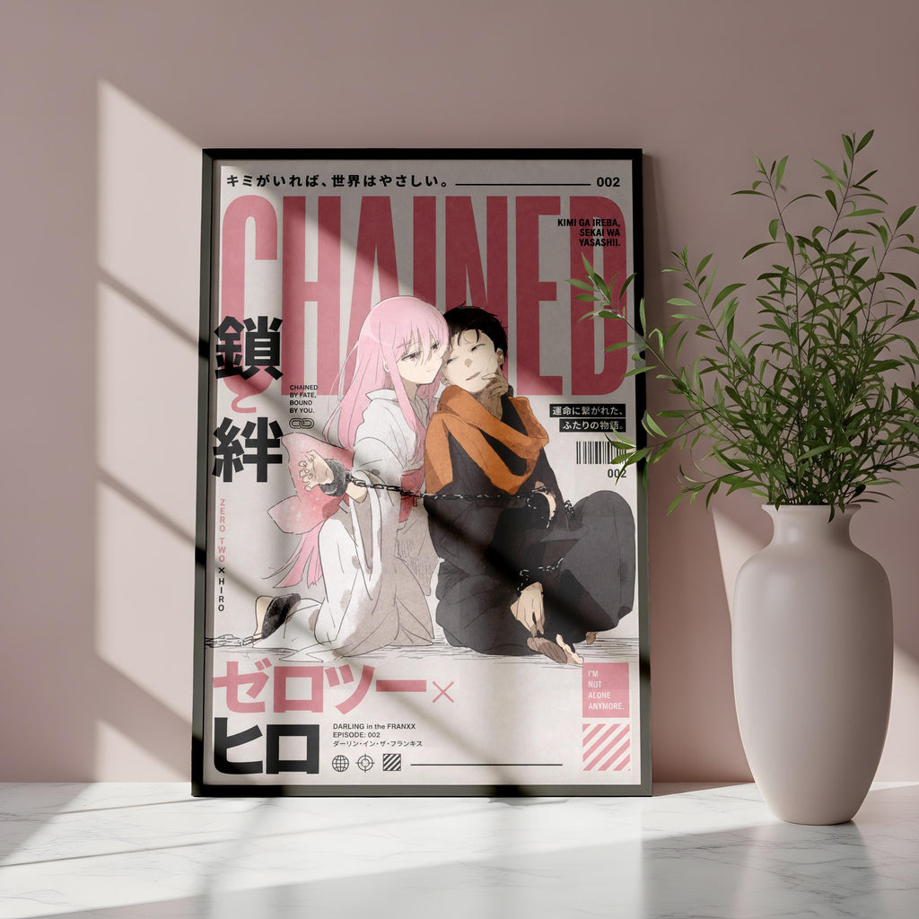 The image is a framed poster featuring an anime-style illustration of two characters, one with pink hair and the other with dark hair, sitting together. The poster has a pink and black color scheme and includes Japanese text. The poster is displayed on a pink wall, and there is a white vase with a plant to the right of the poster.