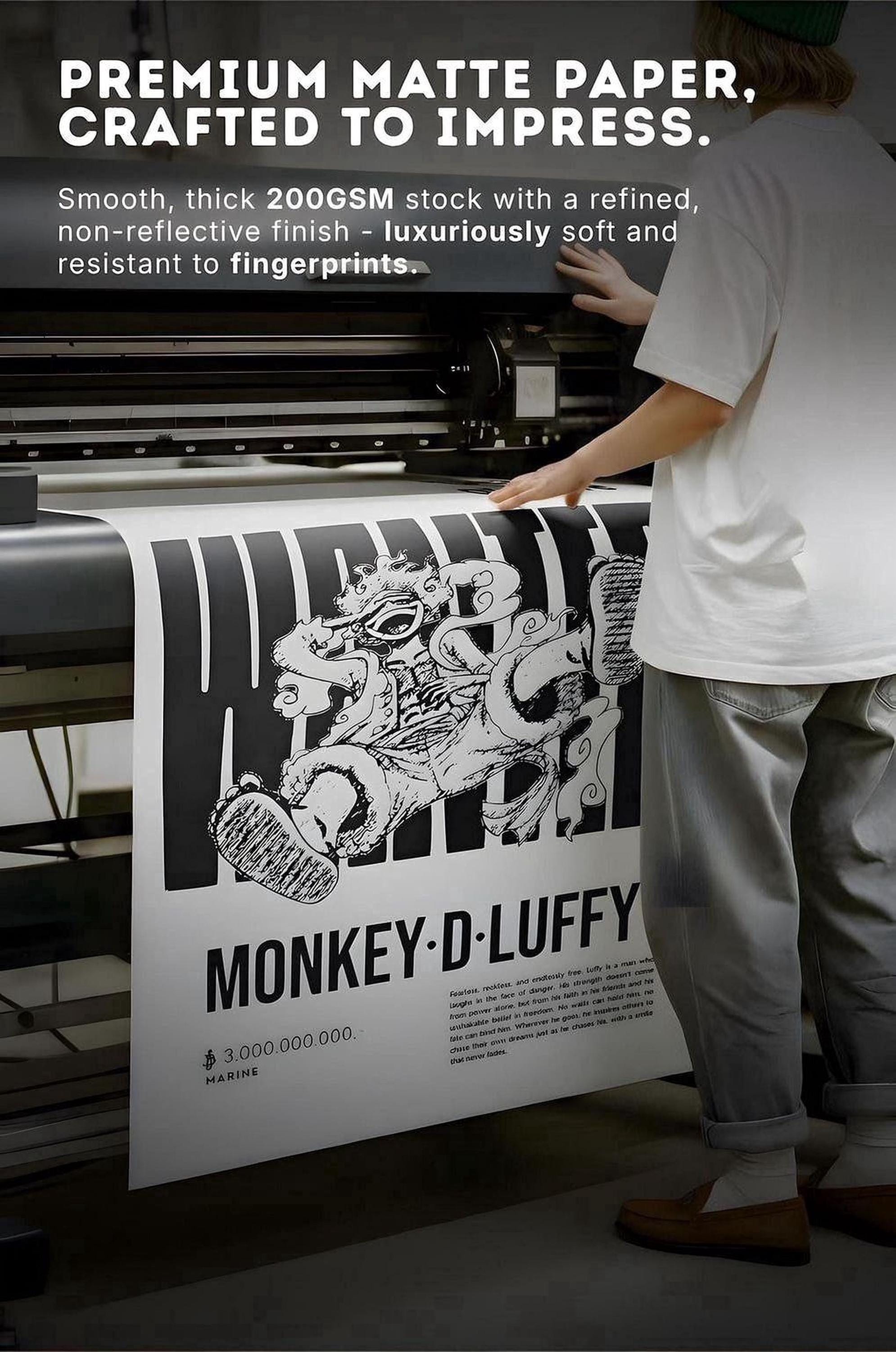 a person operating a printing press, with a large poster or banner prominently displayed in the foreground. The poster has a striking black and white design with a monkey-like figure, and the text on the poster reads "MONKEY-D-LUFFY".